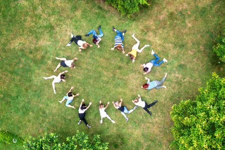 Top view of people standing in circle on green grass doing exercisesの写真素材