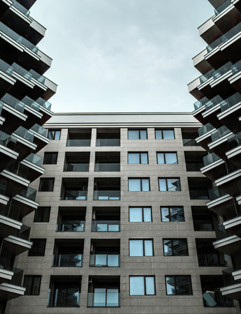 Low angle view of facade through buildings on sides, with angular balconies with glass railings.の写真素材