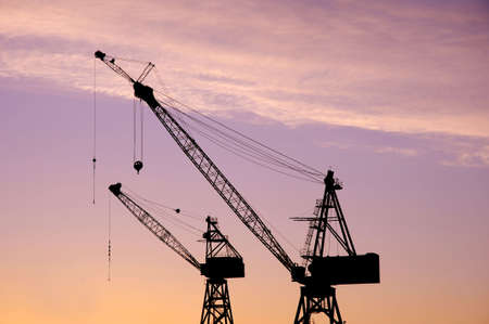 Silhouette of cranes above a building site at sun riseの写真素材