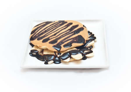 a white plate on a white sheet on which there is a pancake with banana chocolateの写真素材