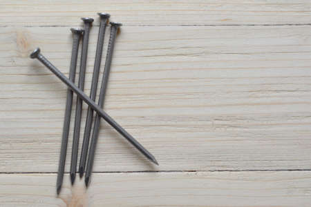 On a worn-out stick, four nails are stacked side by side. The fifth is placed on them
