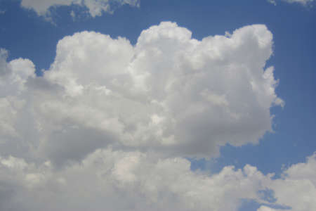 in a large white interesting form the cloud is seen about the approach of rain in the sky above the blue colorの写真素材