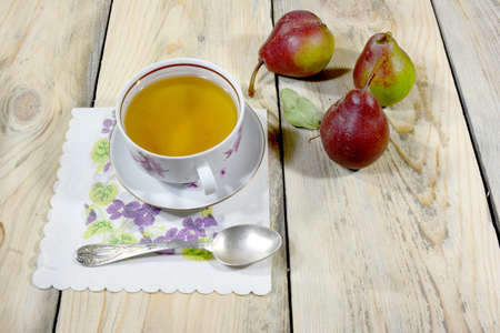 A beautiful cup of tea is lying on a table made of worn-out shoes, there are also three delicious pears on the tableの写真素材