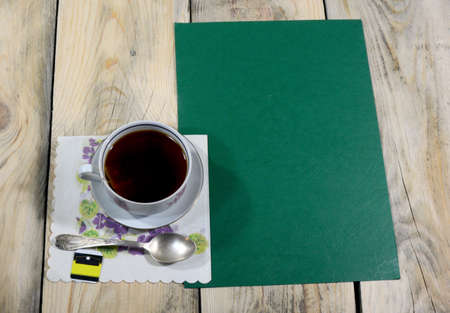 A beautiful cup of iced tea is placed on a table made of worn wood, on the table there is a teaspoon and a napkin.の写真素材