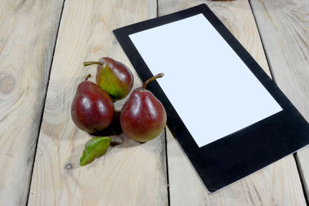 Three beautiful delicious ecologically clean pears and a white paper lined with black are placed on a table made of worn woodの写真素材