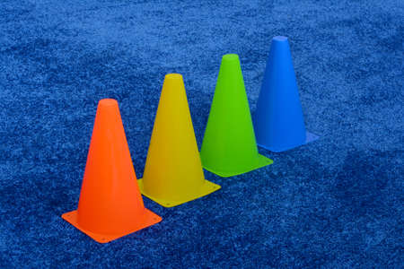 blue red green yellow yellow sports cones neatly arranged on a blue sports matの写真素材