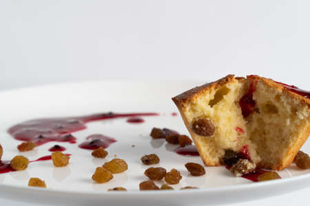 Sweet homemade cupcake with raisins and drops of jam on a white plate.の写真素材