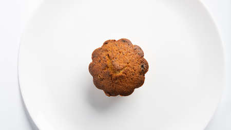Sweet homemade cupcake with raisins on a white plate.