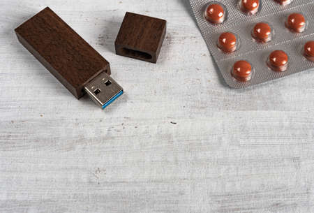 Flash drive in wooden case on gray structured background next to tablets. Store information on the composition and use of medicines online.の写真素材