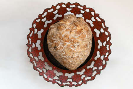 Whole celery root on a metal plate with an ornament in natural light.