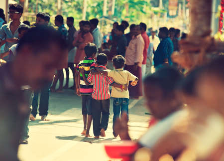 India. Kerala. Three young friends walking through crowd.のeditorial素材