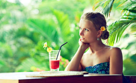 Relaxed young woman, surrounded green plants, resting with cocktail  Vacation and leisure.の写真素材