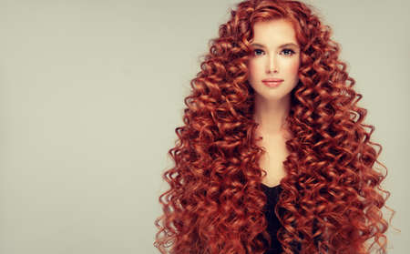 Portrait of young, attractive young model with incredible dense, long, curly red hair.Frizzy hair.