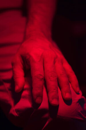 Hand of injured patient receiving treament under red rehabilitation hospital clinic heat lamp.の写真素材