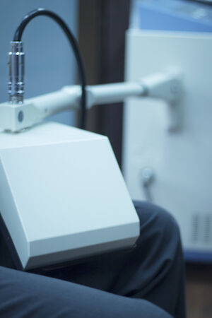 Rehabilitation from traumatology and orthopedic surgery physiotherapy machine with patient undergoing treatment on thigh injury in hospital clinic. Color digital photo in blue tones.の写真素材