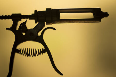 Vintage traumatology and orthopedic surgery syringe in silhouette against a plain studio background.の写真素材