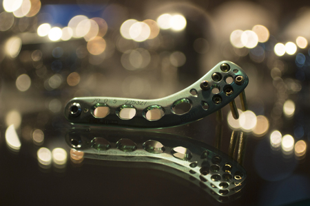 Trauma and orthopedic surgery green titanium implant with screw with reflection and bokeh light effect. Still life color digital photo in brown tones.の写真素材