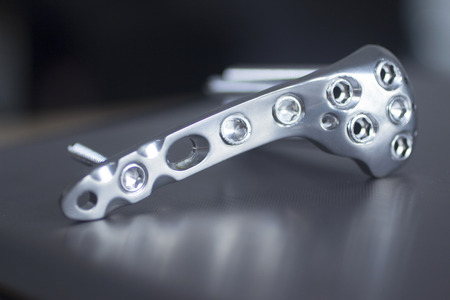 Trauma and orthopedic surgery metal implant with screws with reflection and bokeh light effect. Still life color digital photo in blue tones.の写真素材
