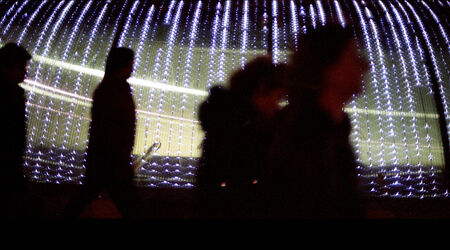 Silhouette of people walking in urban city street at night with background of led lights. Artistic...