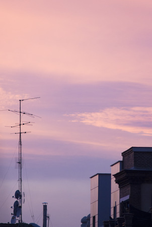 TV arial television antenna tied with metal cables onto roof of an urban high rise building and blue purple dusk sunset sky in Madrid Spain.の写真素材