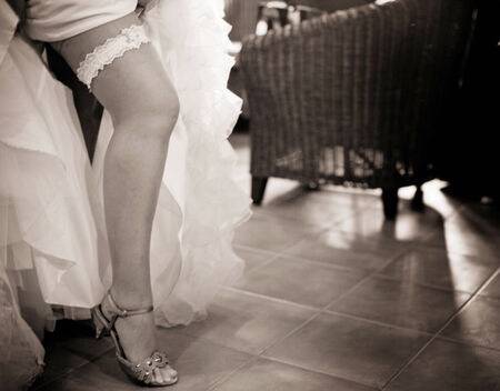 Young exhibitionist bride in wedding and garter belt stockings lingerie showing legs in public in wedding reception party bar.の写真素材