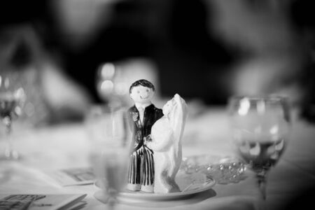 Wedding cake topper figurine bridegroom bride on wedding reception marriage banquet table black and white photo.の写真素材