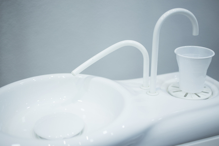 Dentist's water cup tap pip filler in dental clinic in artistic blue purple white tones.の写真素材