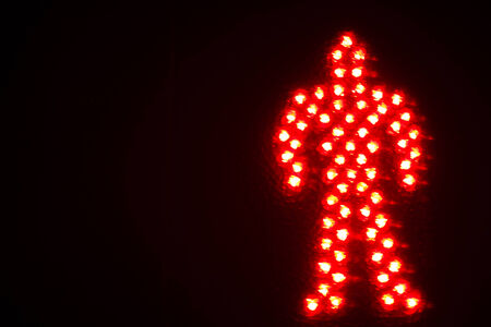 Red man pedestrian stop traffic light photo at night on black background.の写真素材
