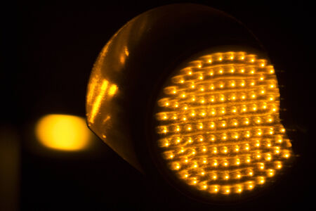 Orange amber traffic light photo at night on black background.の写真素材