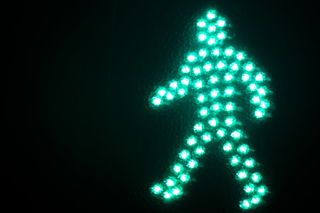 Green man go pedestrian traffic light photo at night on black background.の写真素材