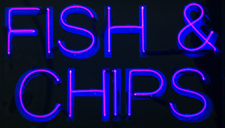 Fish and chips restaurant neon sign at night in street photo.の写真素材