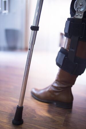 Woman in black jeans and leather boots walking on aluminium metal crutches in hospital clinic.の写真素材
