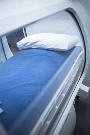 Hyperbaric Oxygen Therapy (HBOT) chamber tank used for specialised medical treatment for injuries in hospital clinic. Exterior viewing window and reflection with pillow and bed inside.の写真素材