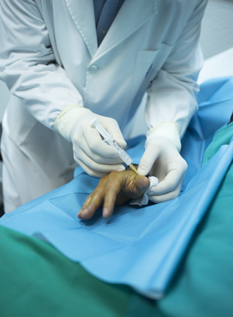 Male Traumatology and Orthopedics surgeon doctor injecting patient on hospital bed in hand and wrist in private clinic with PRP Platelet Rich PLasma Human Growth Factors Stem Cells to treat cartilage wastage joint injury and pain.の写真素材