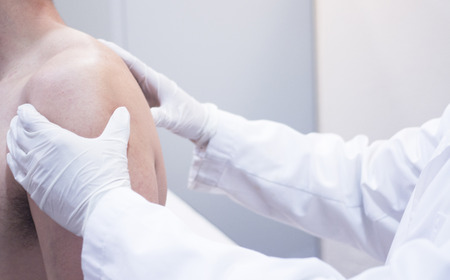 Male Traumatologist orthopedics surgeon doctor examining middle aged man patient to determine injury, pain, mobility and to diagnose medical treatment in shoulder, arm, elbow and wrist.の写真素材