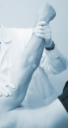 Male Traumatologist orthopedics surgeon doctor examining middle aged man patient to determine injury, pain, mobility and to diagnose medical treatment in shoulder, arm, elbow and wrist.の写真素材
