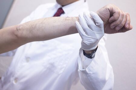 Male Traumatologist orthopedics surgeon doctor examining middle aged man patient to determine injury, pain, mobility and to diagnose medical treatment in shoulder, arm, elbow and wrist.の写真素材