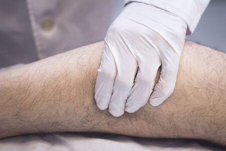 Male Traumatologist orthopedics surgeon doctor examining middle aged man patient to determine injury, pain, mobility and to diagnose medical treatment for foot, ankle, leg and calf.の写真素材