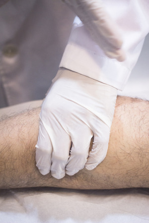 Male Traumatologist orthopedics surgeon doctor examining middle aged man patient to determine injury, pain, mobility and to diagnose medical treatment for foot, ankle, leg and calf.の写真素材