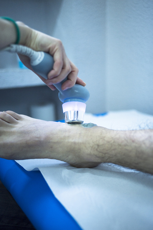 Electro stimulation used to treat pain, muscles injuries, strains and tension in hospital physiotherapy medical rehabilitation clinic for patient foot, heel and ankle.の写真素材