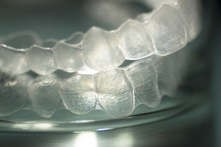 Invisible Invisalign plastic dental teeth brackets tooth braces isolated with shallow depth of focus artistic photograph.の写真素材