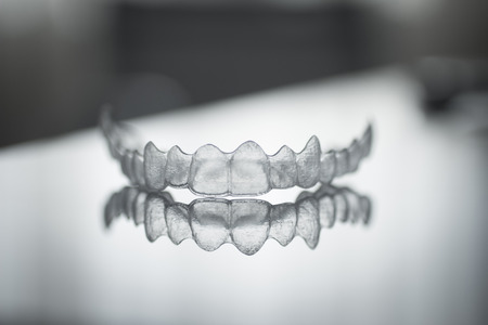 Invisible Invisalign plastic dental teeth brackets tooth braces isolated with shallow depth of focus artistic photograph.の写真素材