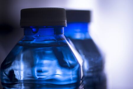 Isolated plastic water bottle on a plain blue studio background close-up photograph.の写真素材