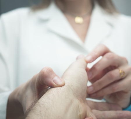 Female Traumatologist orthopedic surgeon doctor examining middle aged man patient to determine injury, pain, mobility and to diagnose medical treatment in shoulder, arm, elbow, wrist and fingers.の写真素材