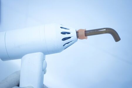 Dental filling gun in dentist hand in clinic office photo.の写真素材