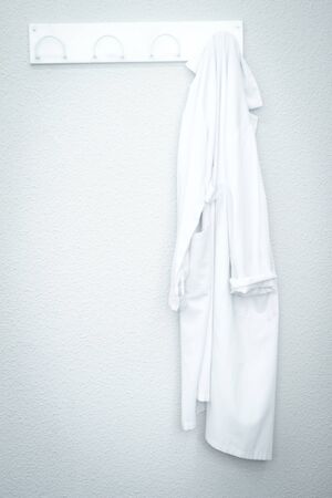 White medical coat laboratory uniform in hospital clinic on wall on coat hangar.の写真素材