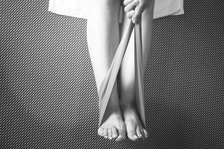 Pilates stretching leg hamstring foot achiles tendon yoga flexibility postural rubber band posture blue flexible strap health club held by young woman exercising.の写真素材