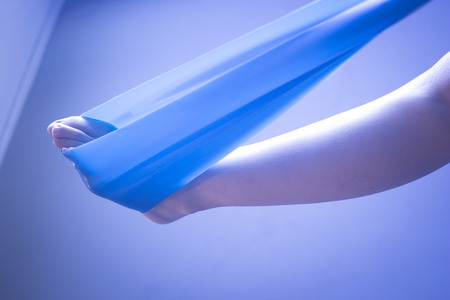 Pilates stretching leg hamstring foot achiles tendon yoga flexibility postural rubber band posture blue flexible strap health club held by young woman exercising.の写真素材
