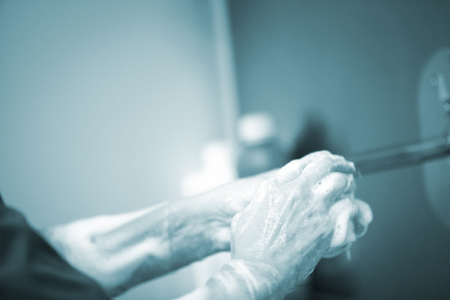 Traumatology orthopedic surgery hospital emergency operating room prepared for arthroscopy operation photo of nurse scrubbing doctor washing hands sterilising with sterilisation soap and products.の写真素材