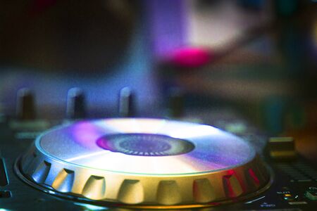 DJ console cd mp4 deejay mixing desk Ibiza house techno dance music wedding reception party in nightclub with colored lighting effect disco lights.の写真素材